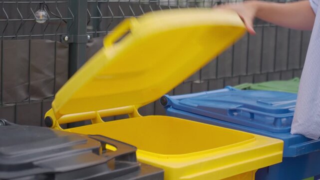 Woman throws plastic bottle into yellow recycling bin for household waste sorting. Concept of plastic recycling and responsible waste disposal