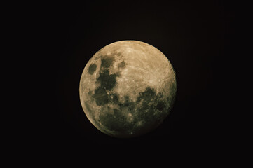 Detailed close-up of a glowing full moon showing lunar craters against a pitch black night sky. © Gates Studio
