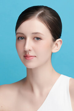A beautiful young Asian woman with clean, fresh skin against a blue background. Skincare, facial treatment, cosmetology, beauty, and spa. An elegant portrait of an Asian woman.