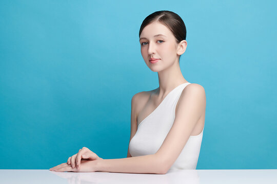 A beautiful young Asian woman with clean, fresh skin against a blue background. Skincare, facial treatment, cosmetology, beauty, and spa. An elegant portrait of an Asian woman.