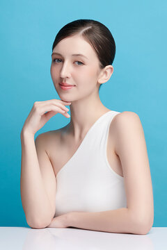 A beautiful young Asian woman with clean, fresh skin against a blue background. Skincare, facial treatment, cosmetology, beauty, and spa. An elegant portrait of an Asian woman.