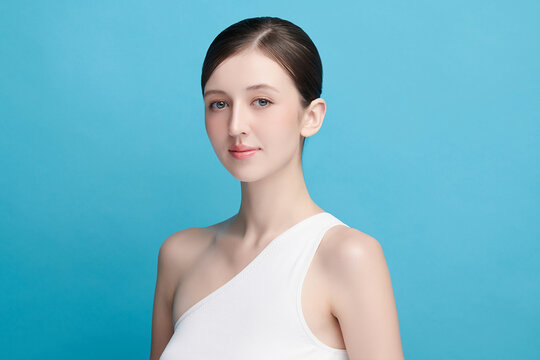 A beautiful young Asian woman with clean, fresh skin against a blue background. Skincare, facial treatment, cosmetology, beauty, and spa. An elegant portrait of an Asian woman.