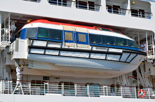 Lifeboats on a modern white passenger liner are essential safety craft usually painted bright orange or white, mounted on metal davits along the ship's sides, 