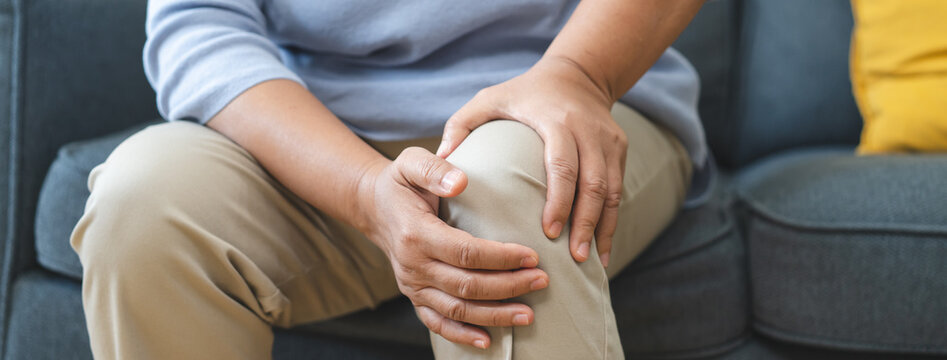 Arthritis is a chronic disease problem in elderly healthcare, Asian old female touching her leg feeling pain in her knee joint, and can't walk properly because of inflammation and pain