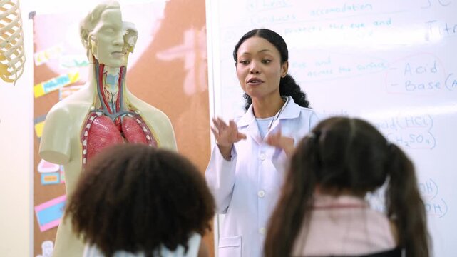 African American science teacher explaining anatomy to students in classroom