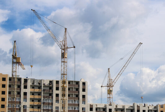 A multi-storey residential building under construction with several yellow tower cranes