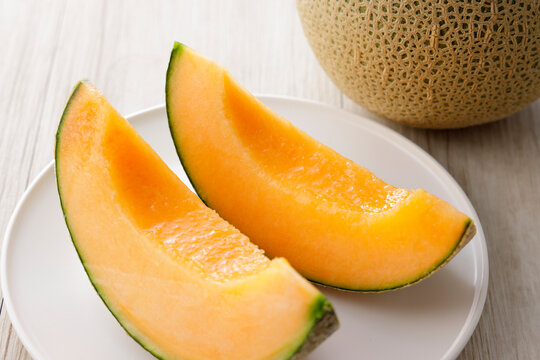 テーブルに置かれた北海道産の赤肉カットメロン　Cut orange flesh Japanese melon on a table, Hokkaido cantaloupe