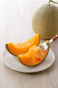 テーブルに置かれた北海道産の赤肉カットメロン　Cut orange flesh Japanese melon on a table, Hokkaido cantaloupe