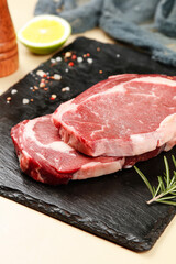 Fototapeta premium Fresh Raw Ribeye Steak Cuts on Slate Board with Herbs and Spices