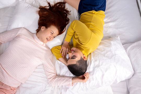Happy Lesbian Couple Lying on Bed Together and Laughing