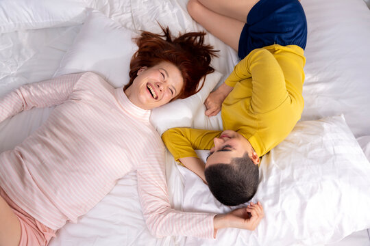 Happy Lesbian Couple Lying on Bed Together and Laughing
