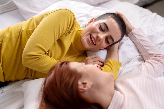 Happy Lesbian Couple Lying on Bed Together and Laughing