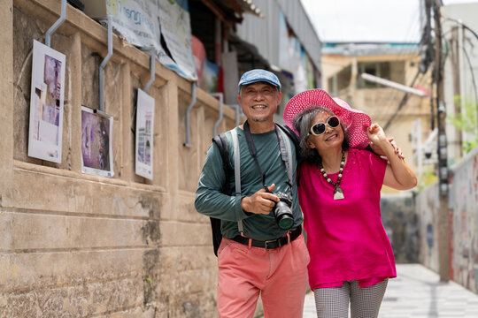 Happy Senior Asian Couple Traveling Together in Urban Alley