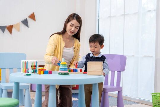 Asian Teacher and Little Boy Playing Educational Wooden Toys Together
