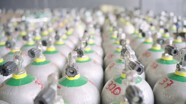 Rows of numbered scuba diving aluminum air tanks stored in a large warehouse