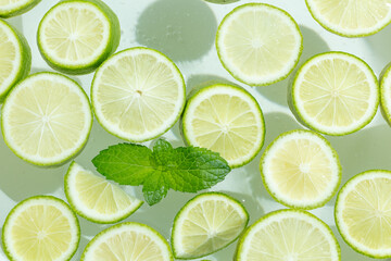 Lime Slices with Mint Leaves on Pale Green Background © NguyenNhat