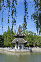 Naklejka premium Chinese pavilion in a park pond with willow branches