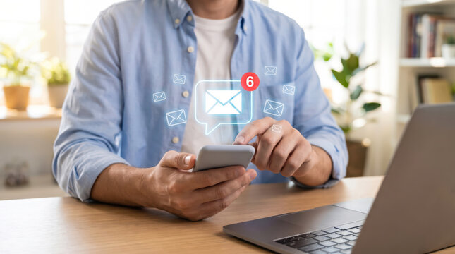 Man Working at Home Desk While Receiving Email Notifications on Smartphone