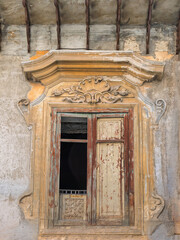 Evocative fine art close-up showcasing the beautiful decay of a 17th-century Baroque window surround in Palermo, contrasting intricate stone shell moldings with a crumbling, textured facade. © Dimitrios