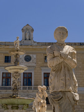 Artistic composition capturing the layered depth of Francesco Camilliani's 16th-century Praetorian Fountain, featuring an expressive marble boundary herm in foreground with Palazzo Pretorio behind.