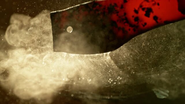 Close-up of glowing hot iron being quenched in cold water. Steam rises, water bubbles and sizzles. Captured in super slow motion with high-speed camera. Concept of metal forging and cooling.