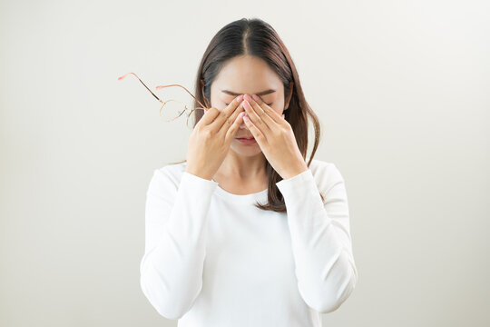 Eye problem concept, fatigue asian young woman tired eyes irritated rubbing, massage eye dry relief vision pain after work, eye strain, hand holding glasses, suffer bad blurry isolated on background.