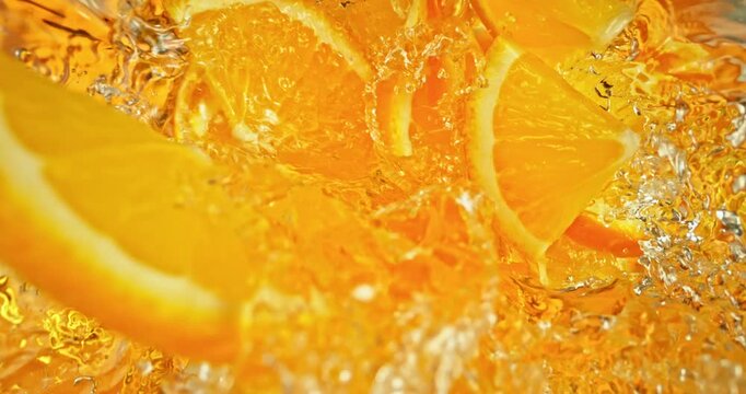 Super slow motion 1000fps video of fresh orange slices falling into rippling water, creating a sparkling splash, perfect for drink, cocktail, beverage and summer visuals.