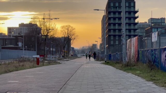 Man and a woman jogging while a cyclist rides during a spring morning sunrise workout