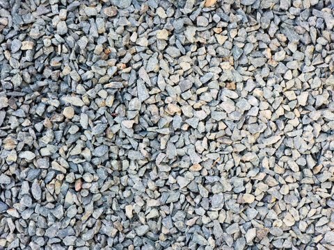 Textural pattern of small gray crushed stones and aggregate gravel spread on the ground
