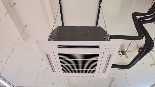 Ceiling-mounted air conditioner with exposed refrigerant pipes wrapped in black elastomeric insulation to prevent condensation, highlighting professional HVAC installation and thermal protection.