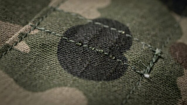 Close-up of military patch featuring black combat insignia on camouflage fabric