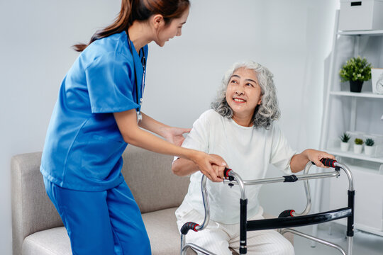 Caring nurse helps older patient practice walking with a support