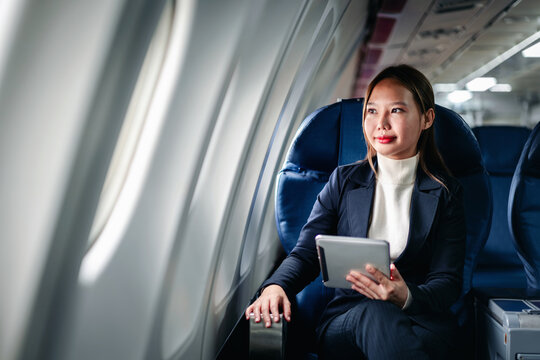 Professional woman using digital tablet airplane window seat wor