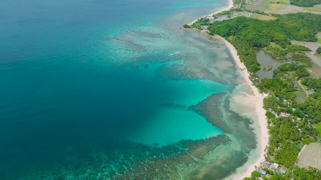 Turquoise water and coral reefs. Paddy farmland and houses in Santa Fe, Tablas, Romblon. Philippines.