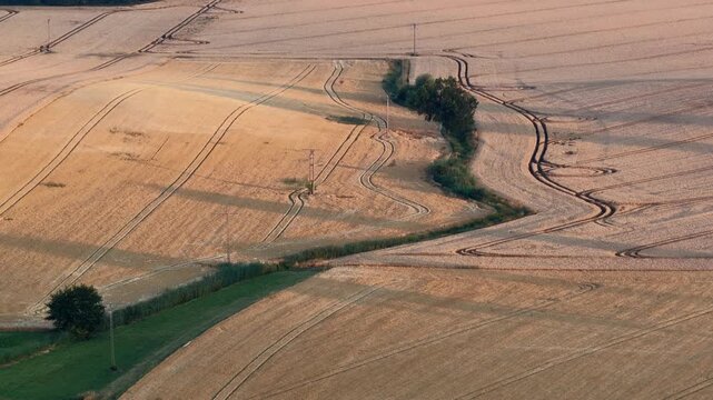 Aerial drone view of rural villages and agricultural fields near Opole and Nysa in Poland, showing geometric farmland patterns, scattered houses, winding country roads and green meadows in daylight.