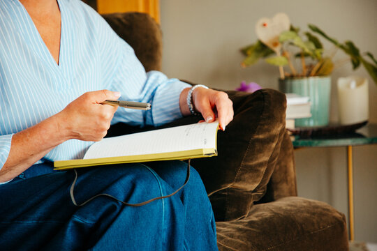 Anonymous woman in smart casual dress writing in a notebook.