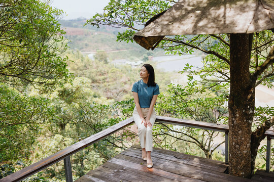 Woman Sitting on Wooden Viewing Deck in Forest Landscape