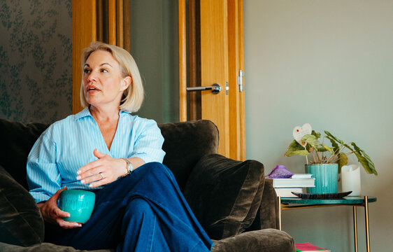Woman holding a coffee cup conversing with someone off camera