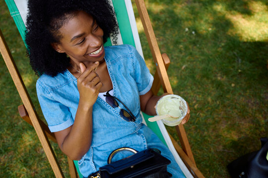 Woman enjoys ice cream while sitting in a deck chair