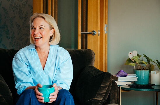 Smiling blonde woman indoors smiling at someone off camera