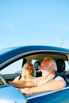 Happy senior couple driving car, enjoying travel together on summer vacation. Experiencing leisure and retired life freedom