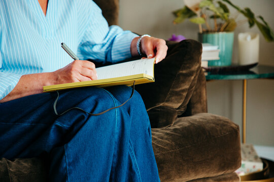 Anonymous woman in smart casual dress writing in a notebook.