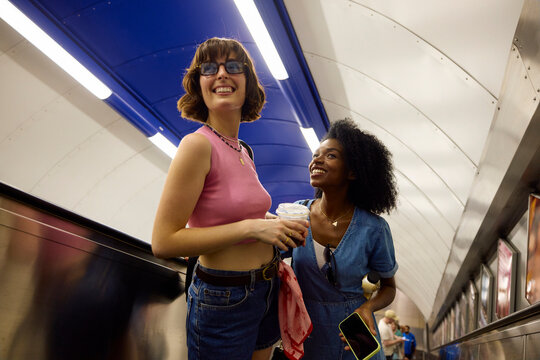 Friends conversing on a subway escalator.