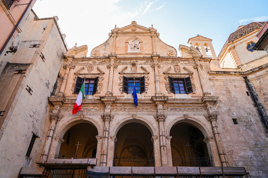 Baroque facade of the Church of Saint Michael with arches and flags in Cagliari, Sardinia, Italy