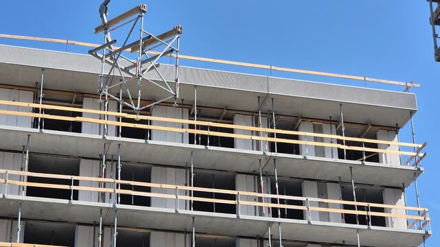 Low angle slow motion shot of Staxo scaffolding being lowered by crane with lifting fork.
