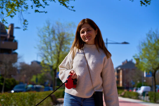 Mature woman walking dog outdoors with retractable leash