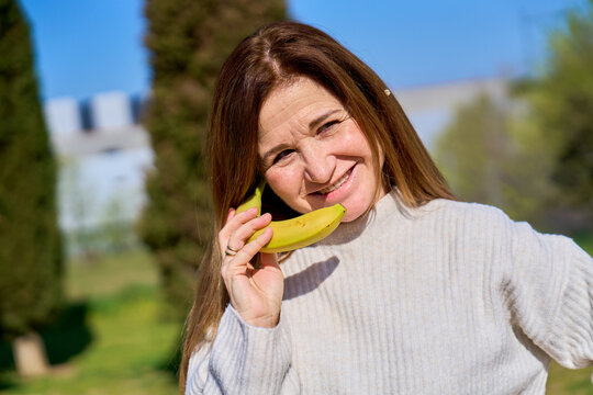 Mature woman smiling, talking on banana phone