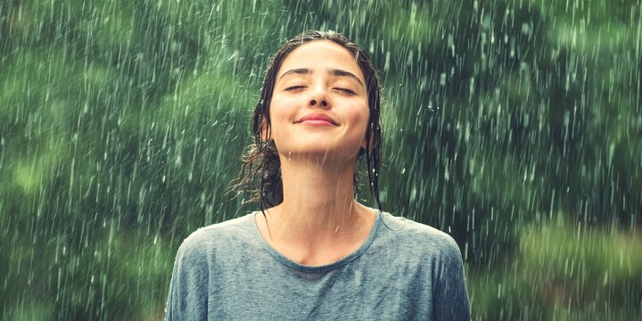 Peaceful individual enjoying the rain with closed eyes fully immersed in the refreshing essence of nature