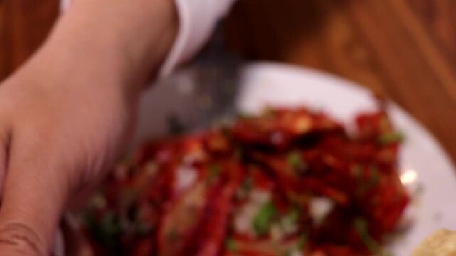 Mujer preparando taco al pastor con cilantro, cebolla y salsa roja. Primer plano de taco al pastor siendo preparado a mano. Mano de mujer agregando salsa roja a taco al pastor. 