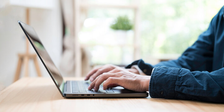 Hands of business man typing during working with laptop computer on the table